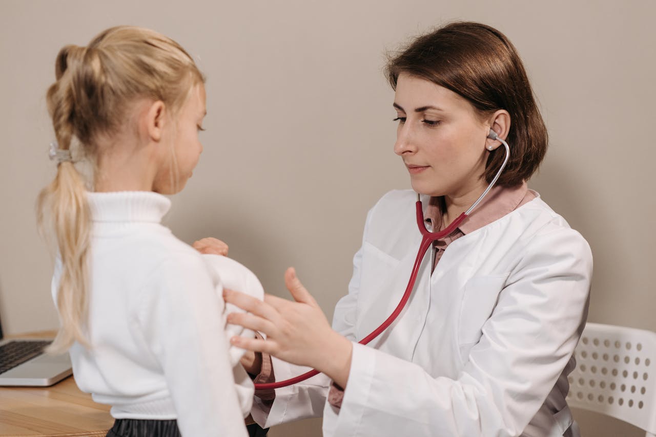 Doctor performing a health check-up on a child using a stethoscope in a clinic setting.